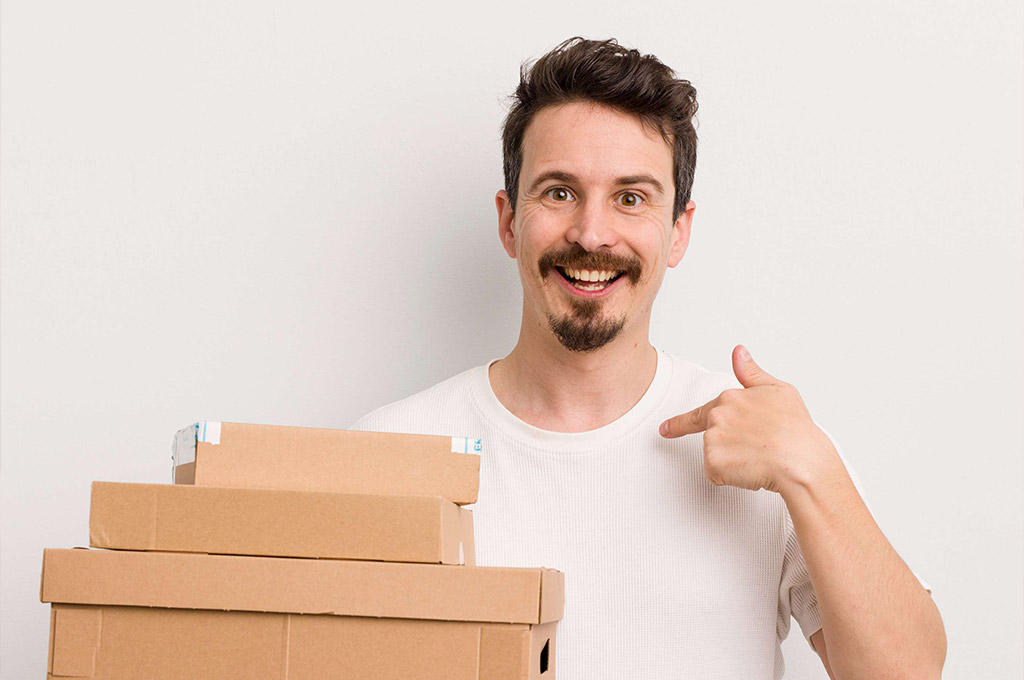 Hombre con pulgar arriba al lado de cajas, feliz con el servicio de almacenamiento